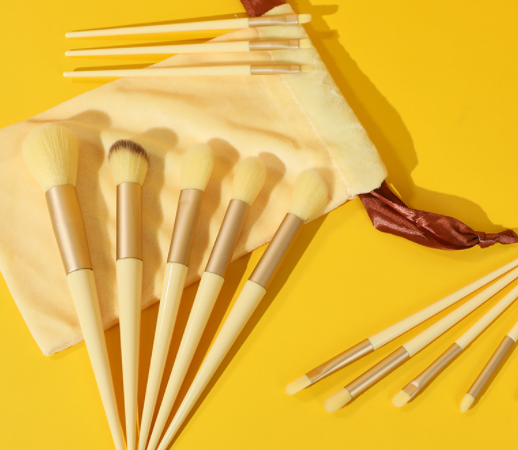 a bunch of makeup brushes sitting on top of a yellow surface